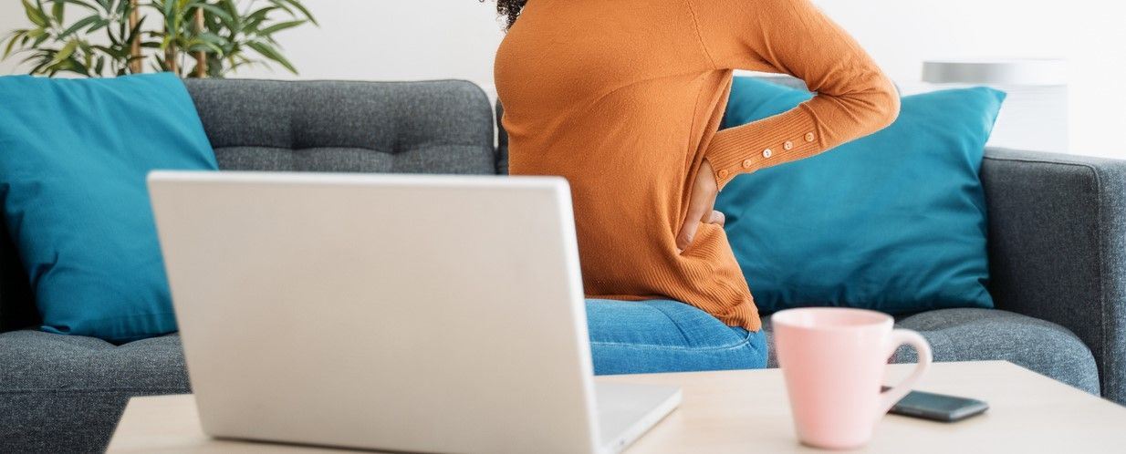 Woman working on laptop with back pain